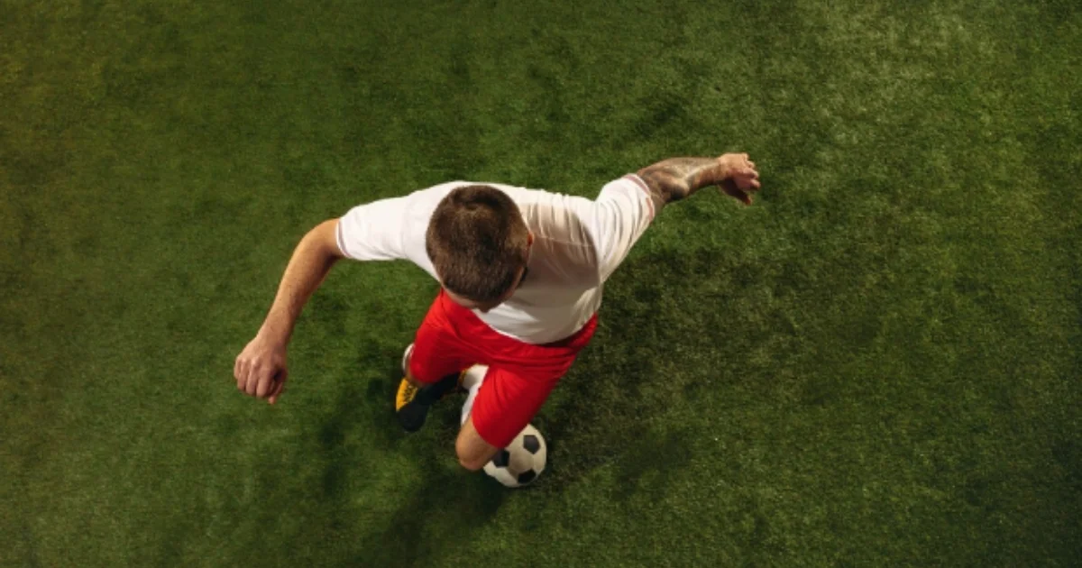 Top-down view of a soccer player controlling a ball on artificial grass.